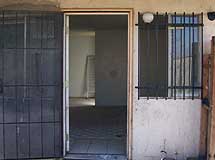 Open front door in trashed, empty house.