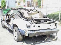 Trashed car parked in front of a house.